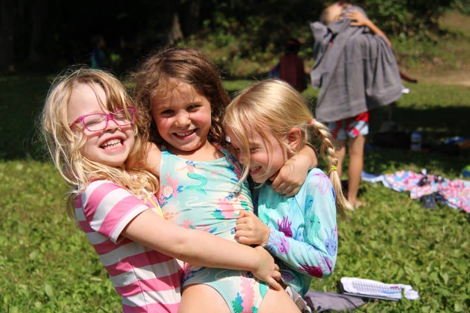 Three girls hug at camp