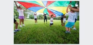 Kidokinetics - Kids play under a parachute