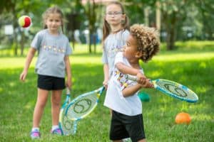 Kidokinetics - Girl hitting ball with racket while other kids watch