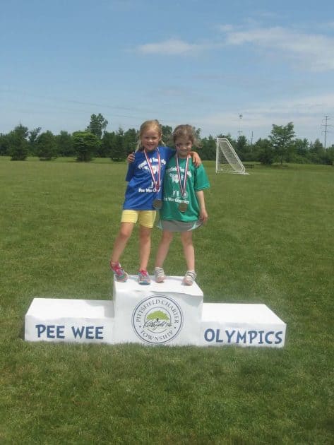 Kids stand on medal stand that says Pee Wee Olympics with the Pittsfield Township seal