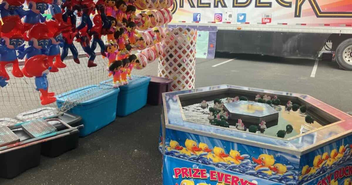 Ann Arbor Jaycees Carnival - Lucky Duck Game - pond of water with floating ducks and inflatable prizes of Papa Smurf, Dora, and Spiderman hanging on the wall