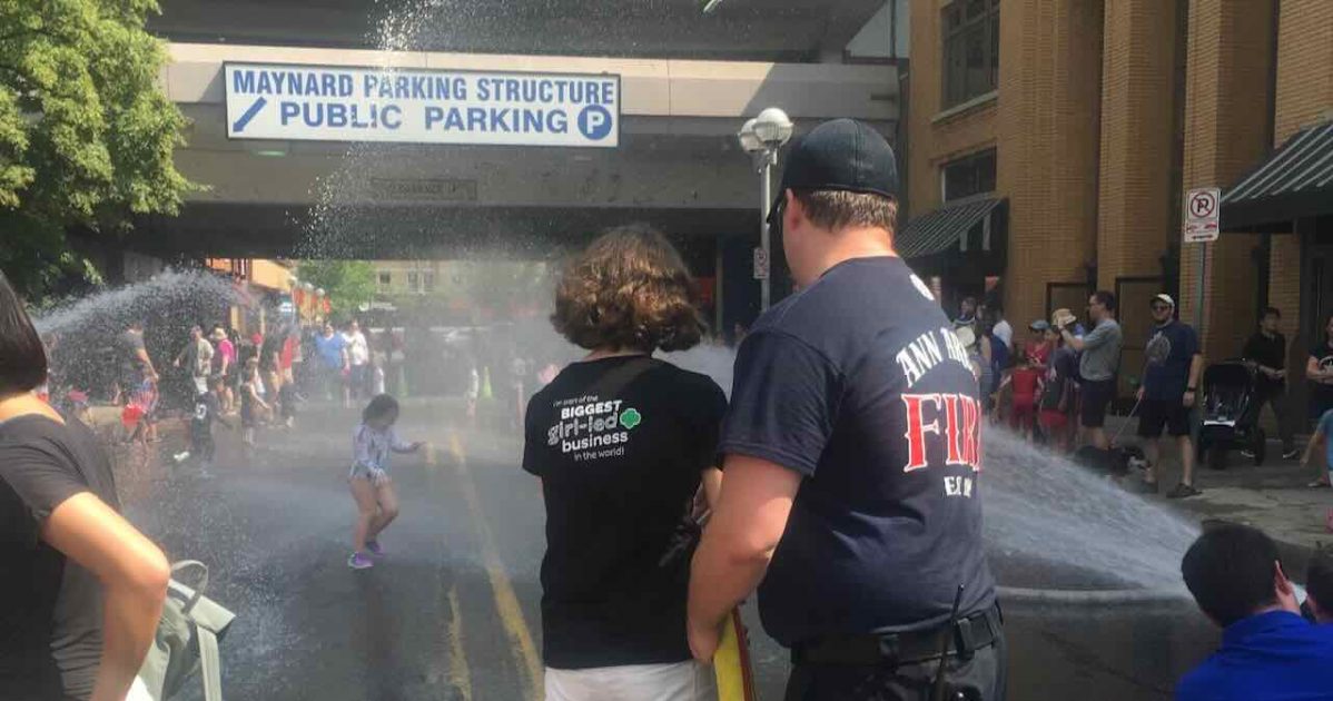 Ann Arbor 4th of July - Firefighters Spray Park 2019 - Firefighter helps teen spray from fire hose