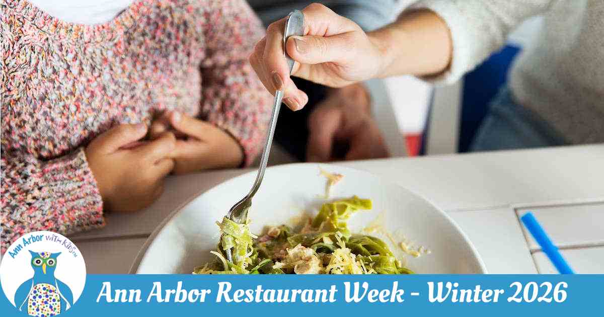 Ann Arbor Restaurant Week Winter 2026 - Parent's hand grabbing forkful of pesto pasta in front of child in pink sweater