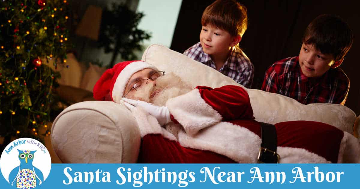 Santa Sightings Near Ann Arbor - Santa sleeping on sofa in front of tree as two boys peek over him.