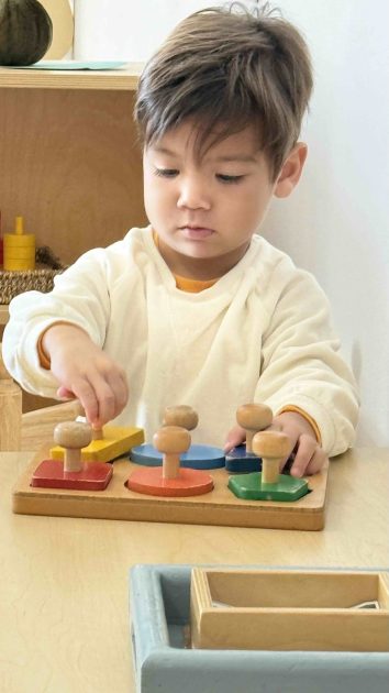Daycroft School - a boy works on a wooden puzzle with large pieces on handles.
