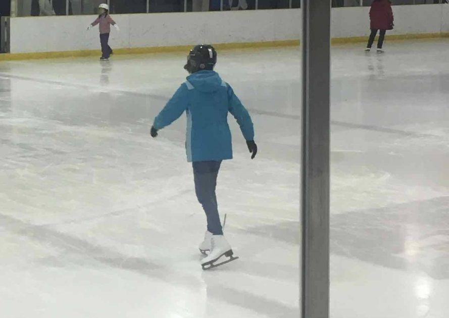 Teen in blue winter coat practices ice skating at Veterans Parks