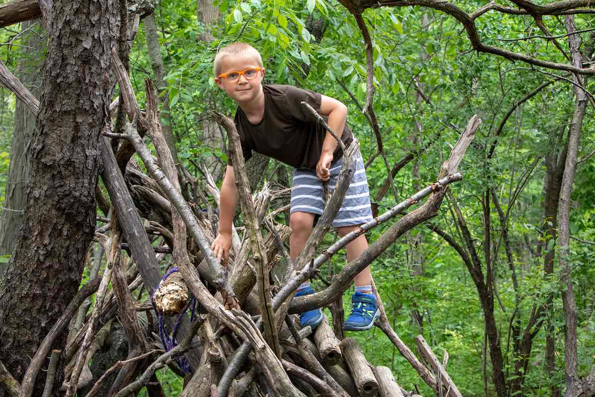 Leslie Science & Nature Center - Nature Playscape  - Boy climbing on structure built from messy build sticks