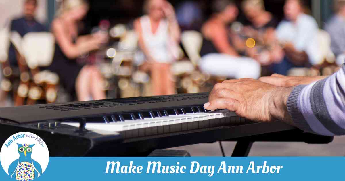 Make Music Day Ann Arbor - A keyboard setup on the street with a musicians hand positioned to play. Audience is blurred in the background.