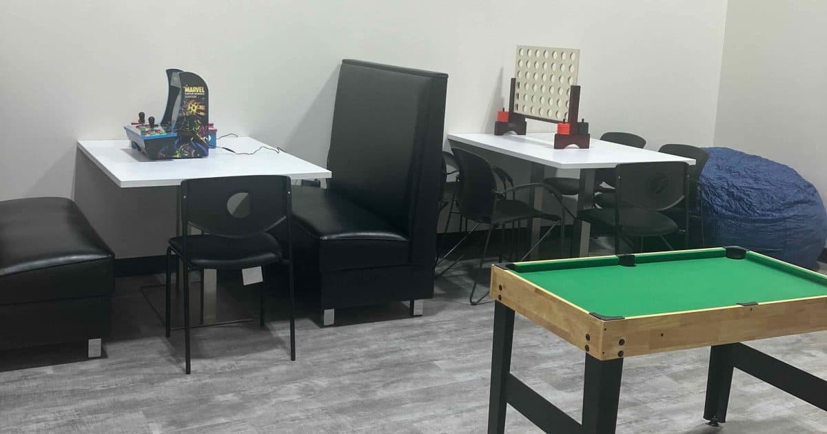 We Rock the Spectrum "teen" hangout room - booth with tabletop video game, Table with Connect 4, large bean bag chair, and a mini-pool table.